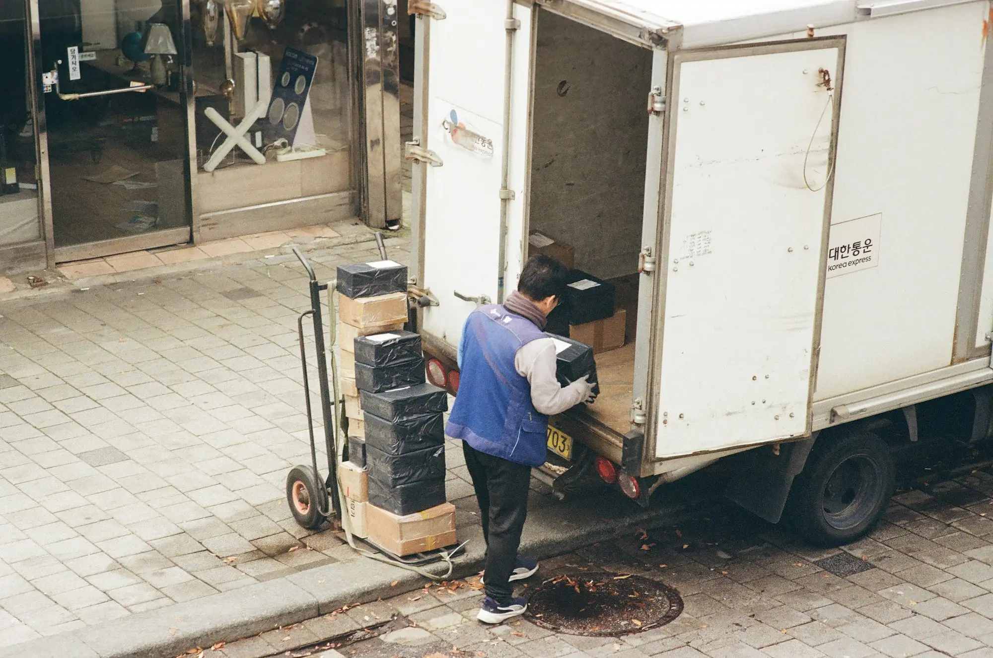 Courier unloading parcels from the back of a white delivery truck