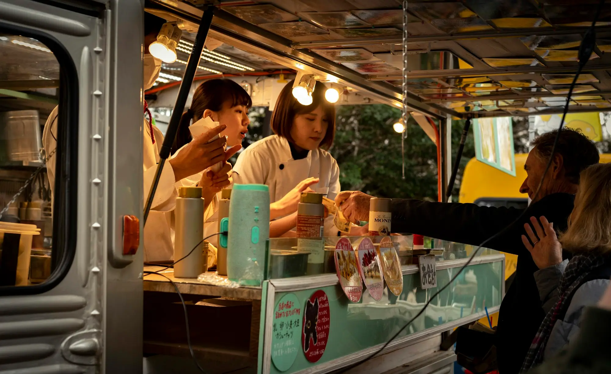 Food truck staff serving customers through the hatch at a busy night market