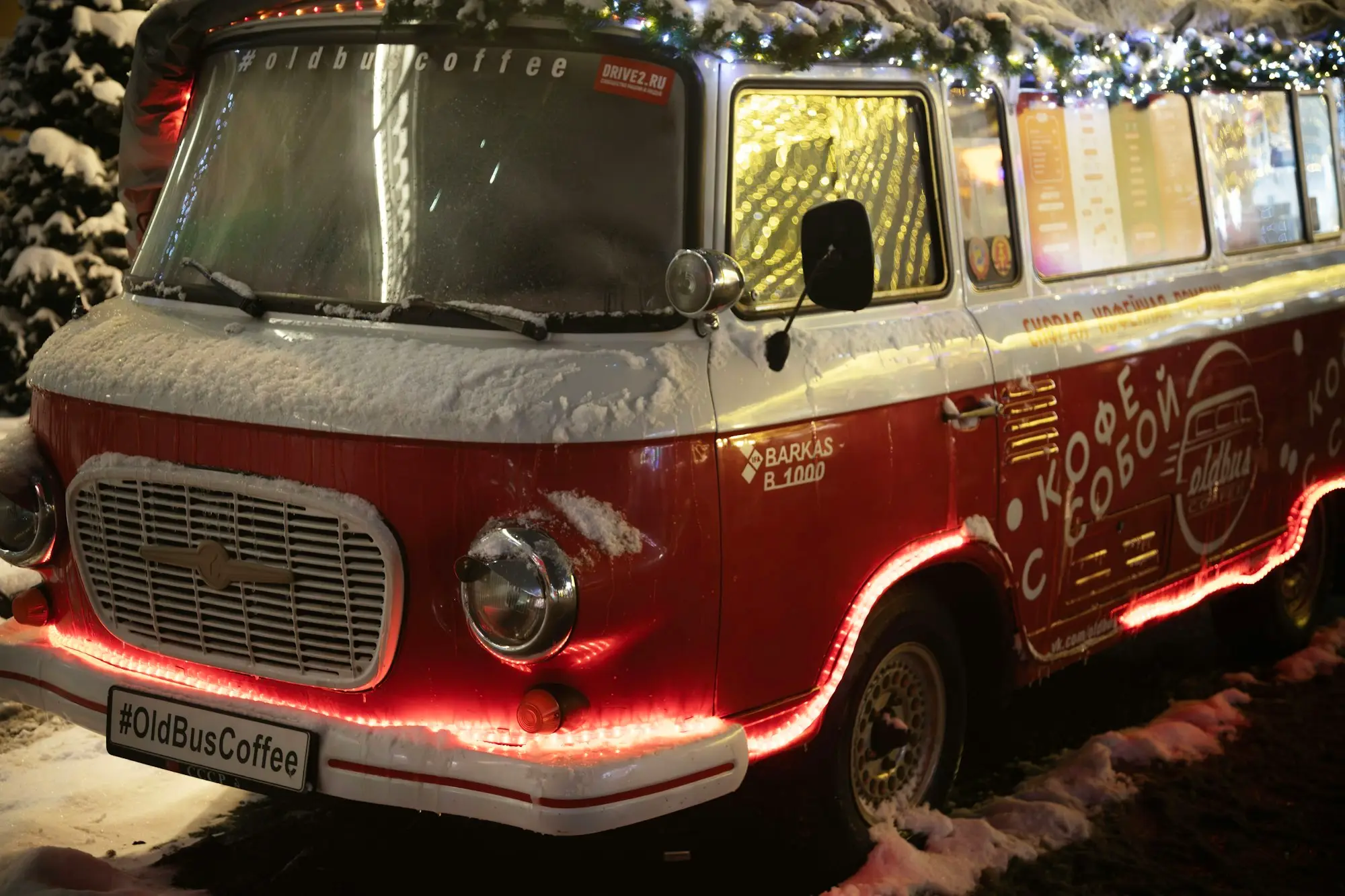 Vintage red coffee van decorated with lights and ready for customers