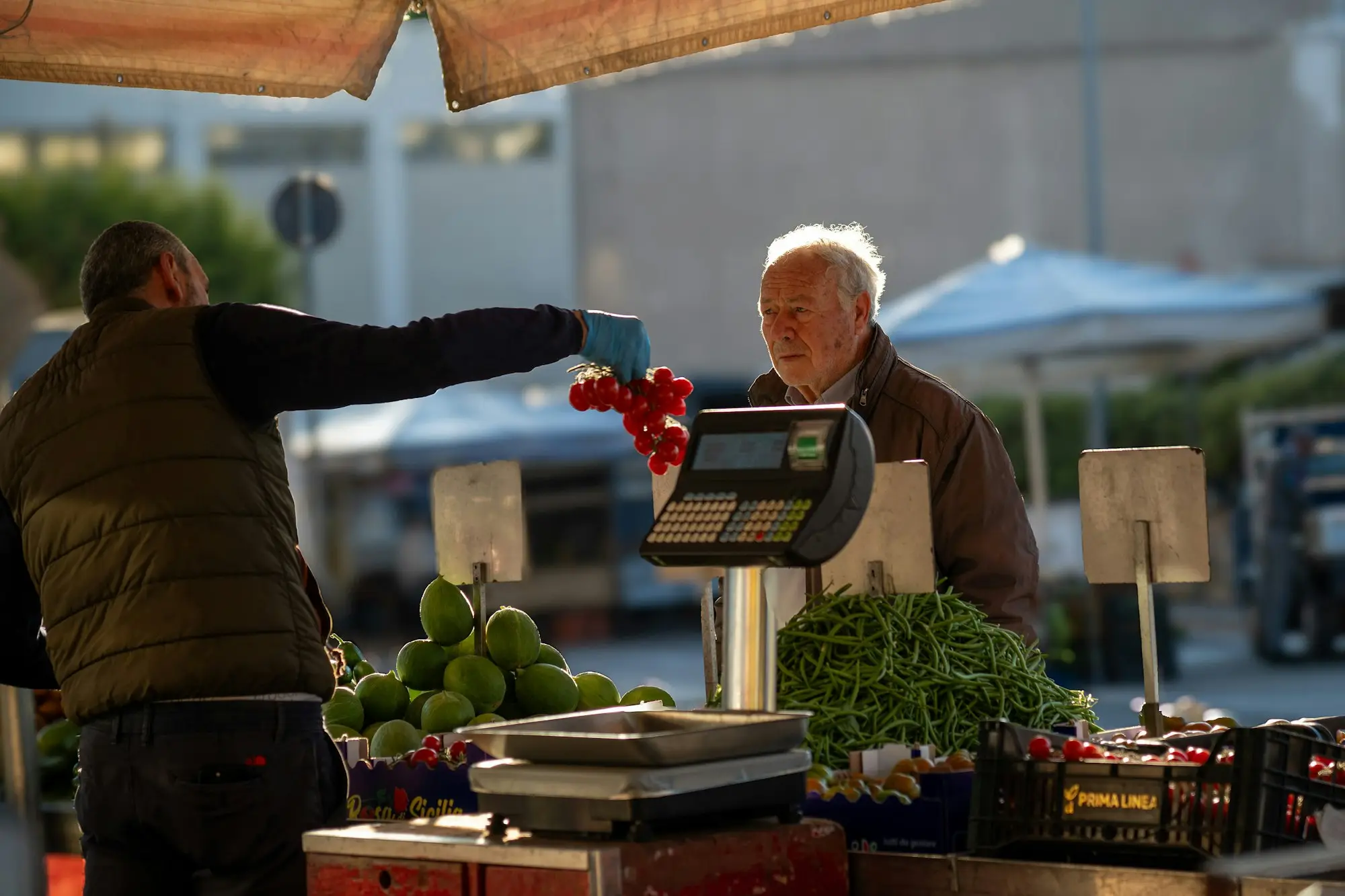 Stallholder weighing produce for a customer at an outdoor market stall